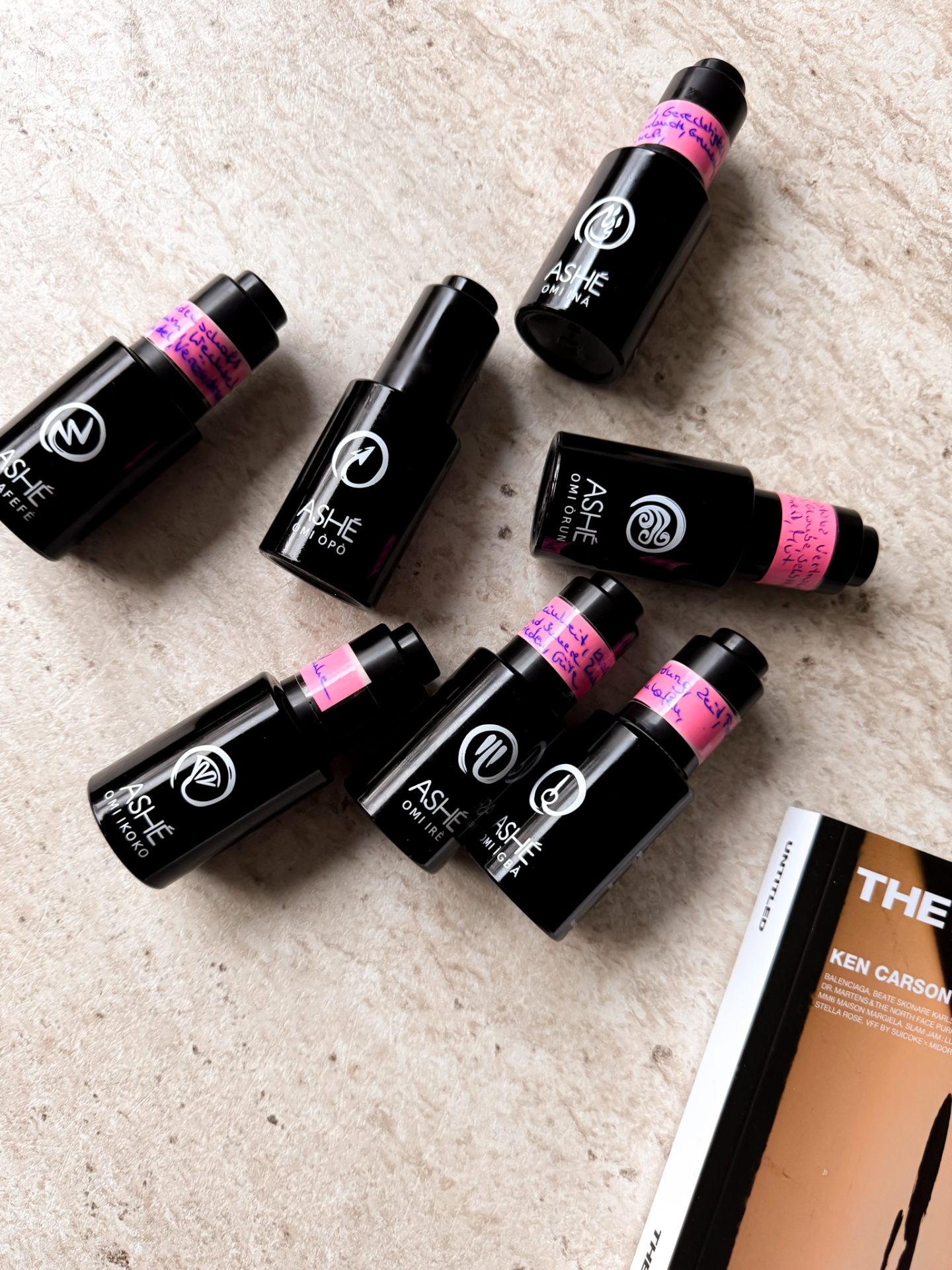 Mehrere Ashé Parfumflakons auf einer Naturstein-Oberfläche, einige mit handbeschrifteten Teststreifen – exklusive Düfte mit einzigartiger Energie.