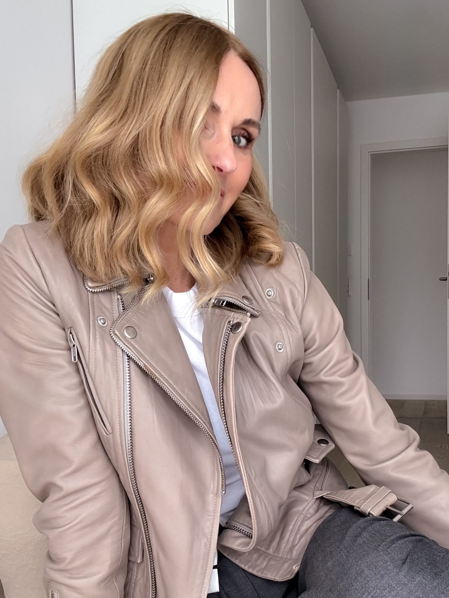 Frau mit Lederjacke in Taupe und dezentem Make-up – moderner Look, der Stärke und Stilbewusstsein ab 50 verkörpert.